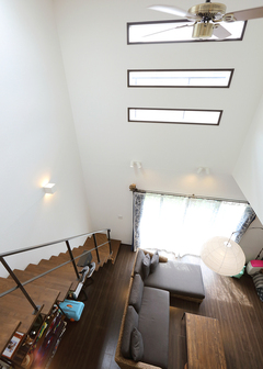 吹抜けを活かした大空間。縦に並んだFIX窓から、採光やブラケットライトの光が注ぎ込む