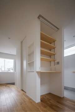 ナチュラルな木製デスクとシェルフが配置されたコンパクトなワークスペース。快適な作業環境を提供する