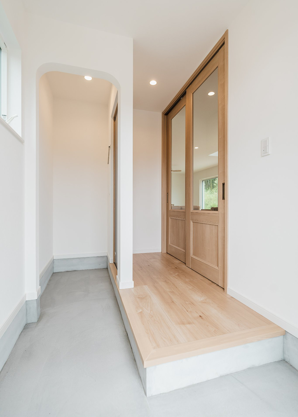 オレンジハウス【デザイン住宅、間取り、ペット】すっきりとした印象の土間玄関。リビングが見えるガラスの引き戸を採用したことで空間に開放感が生まれた
