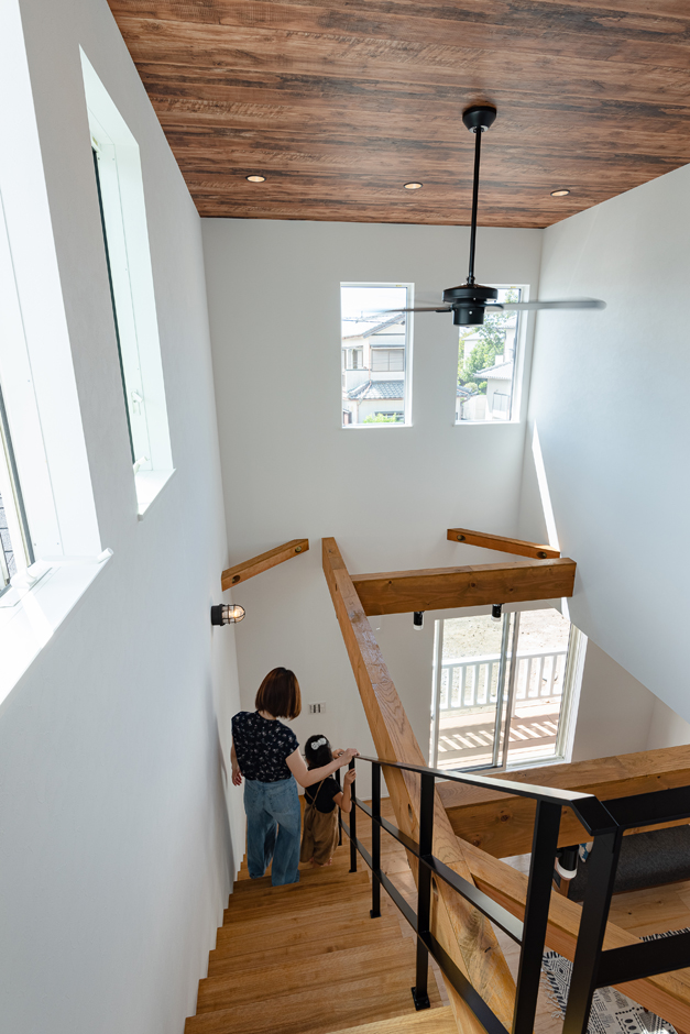 KUREKEN HAUS（榑林建設）【デザイン住宅、省エネ、間取り】リビングの吹き抜けは2階へと続き、どこにいても声と気配が感じられる。
天井は木目のクロスを採用し、ブラックのシーリングファンともベストマッチ。