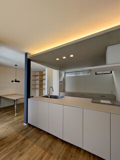 モダンなデザインのキッチンスペース。天井照明が柔らかな雰囲気を演出し、使いやすい広々としたカウンターが魅力的である。