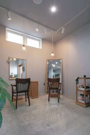 家具や鏡、建具はすべて家具店のオーダーメイド。無機質なグレーの空間に木の家具やアンティーク照明が温かみを添え、グリーンやドライフラワーの彩りが映える