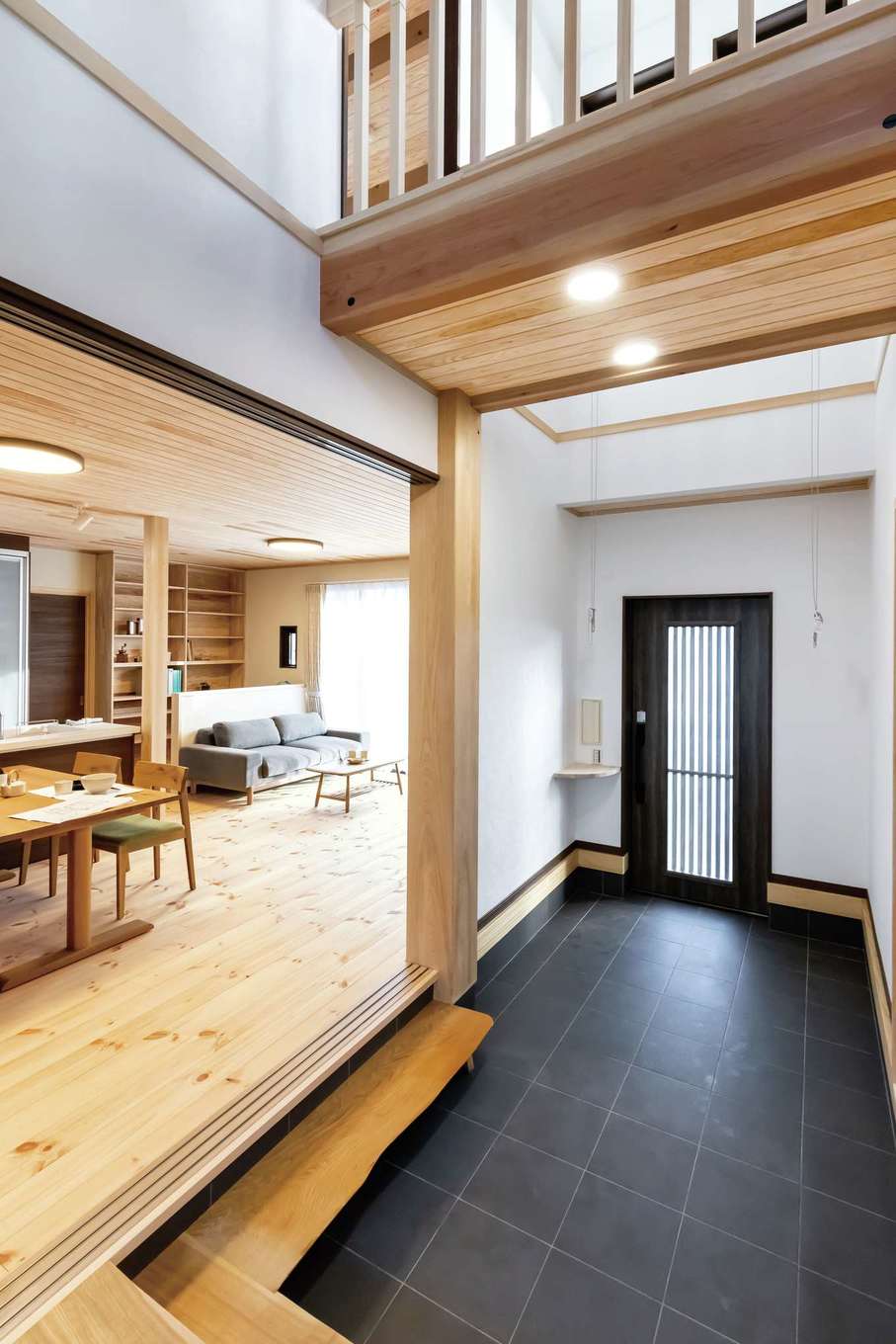 住まいるコーポレーション【子育て、二世帯住宅、自然素材】吹き抜けの玄関。吹き抜けには、2階のLDKと子ども部屋をつなぐ橋のような廊下が、南側と北側に2か所も架かっている