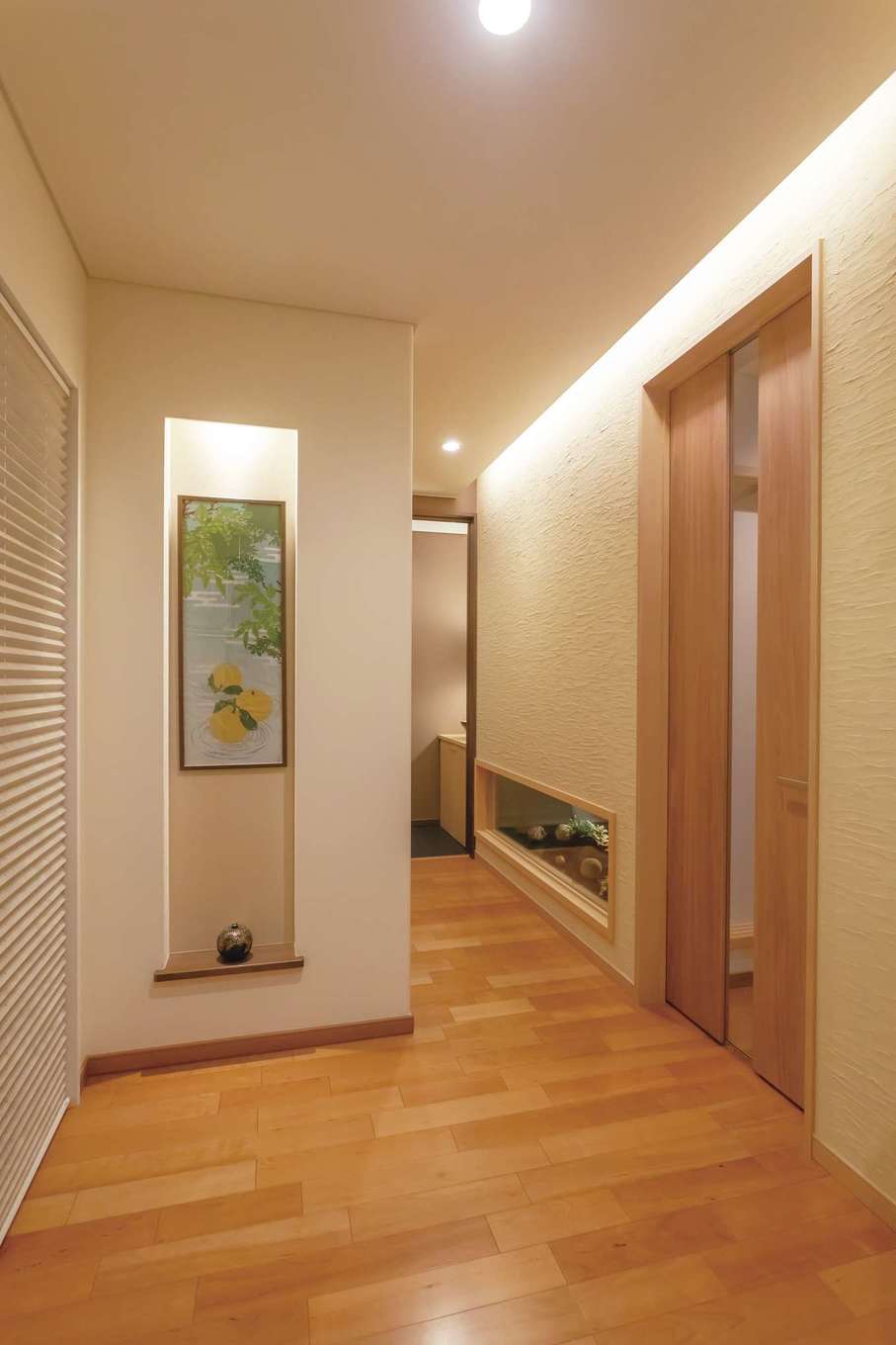 住宅工房 アリアンス【デザイン住宅、趣味、間取り】チーク材の床にランダムごての珪藻土が映える玄関ホール。季節ごとにニッチの手拭いを変え、ゲストをおもてなし