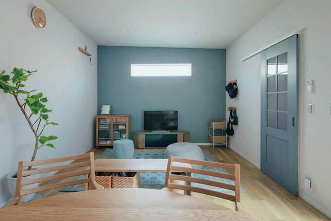 勾配天井のLDKは、差し色にグレイッシュブルーを取り入れてコーディネート。コンパクトなLDKはソファを置かずにすっきりと。限られた広さでも中庭があるから広々と感じられる