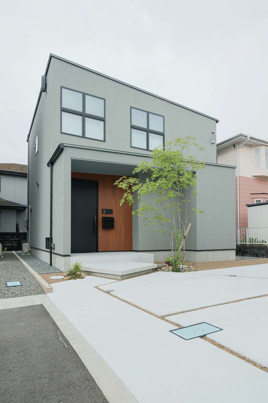 住家 JYUKA【デザイン住宅、間取り、インテリア】塗り壁の外観は、モダンさとやわらかさが調和。玄関回りのレッドシダーと十字窓がほどよい個性を添えている