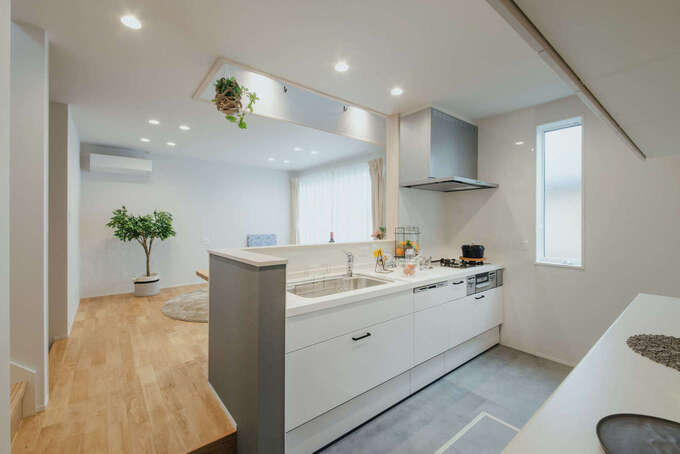 リビングで床に座って過ごす家族と視線を合わせやすくするため、あえて一段下げて設計したキッチン