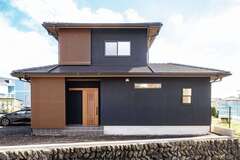 精悍な表情を見せる黒い塗り壁に、格子が和のテイストをプラスする外観