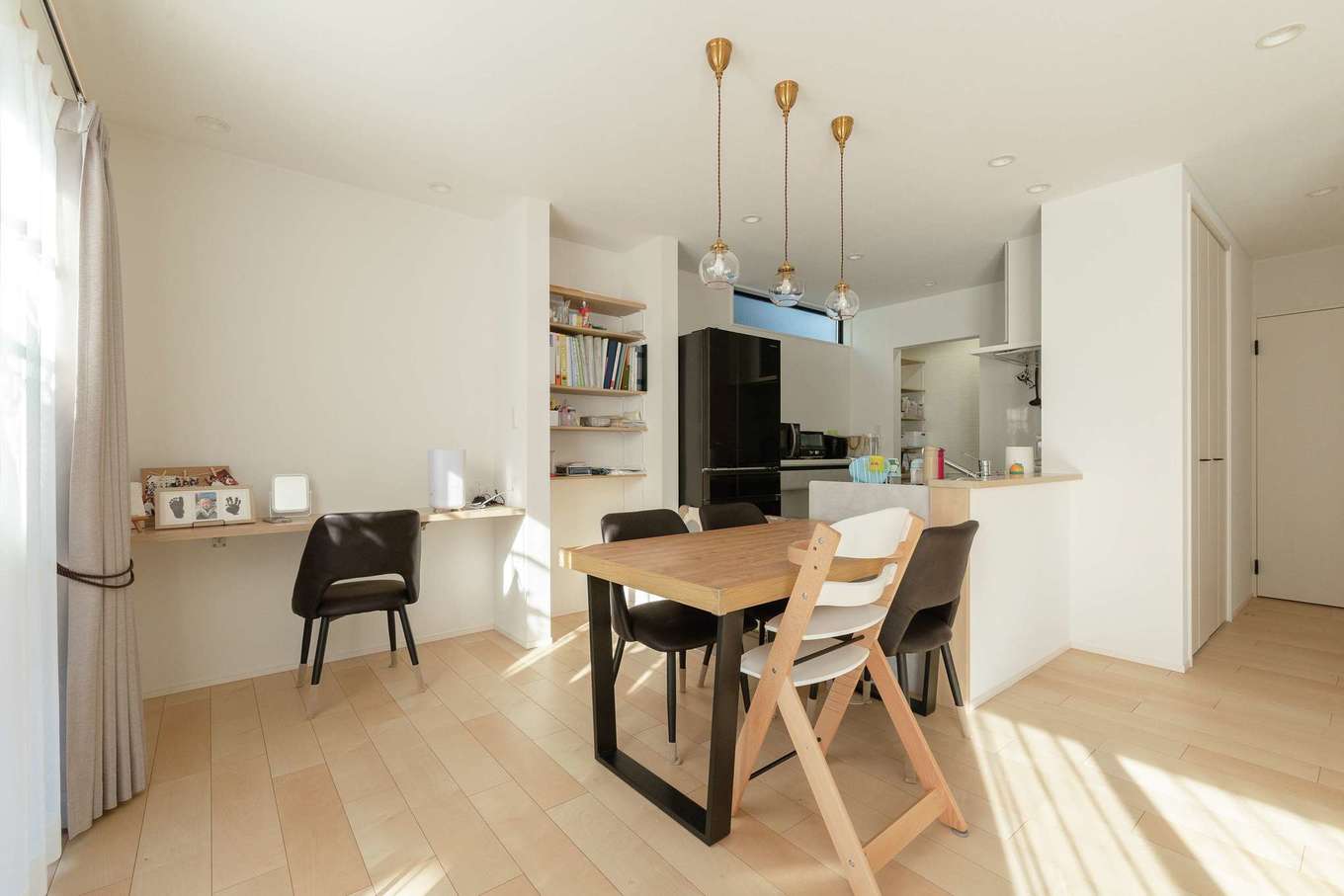 HAPPY HOUSE（山田工務店）【デザイン住宅、子育て、間取り】奥さまお気に入りの照明が雰囲気にマッチする。造作のデスクはディスプレイ、事務仕事、将来の宿題にと多彩な用途に活躍。右のドアを抜けると水回りが続き、玄関に抜けられるようになっている