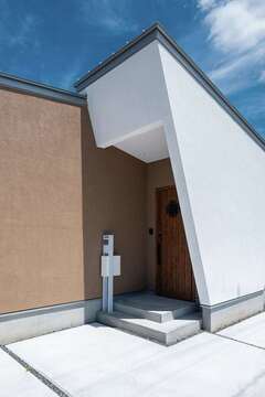 家の前には電車が通っているため、玄関の出入りは直接見えないようにデザイン。エッジの効いた斜めの壁はデザイン性だけでなく、目隠しとしての機能もある