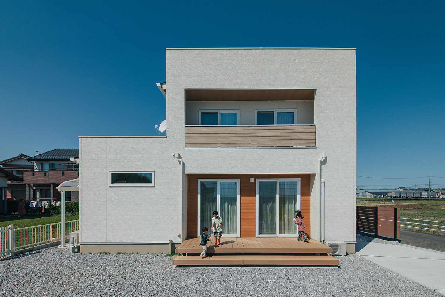 子育て安心住宅 Design Craft Office【デザイン住宅、子育て、間取り】ボックス型の白い外観。南側にウッドデッキを設けてあり、子どもたちの遊び場として大活躍
