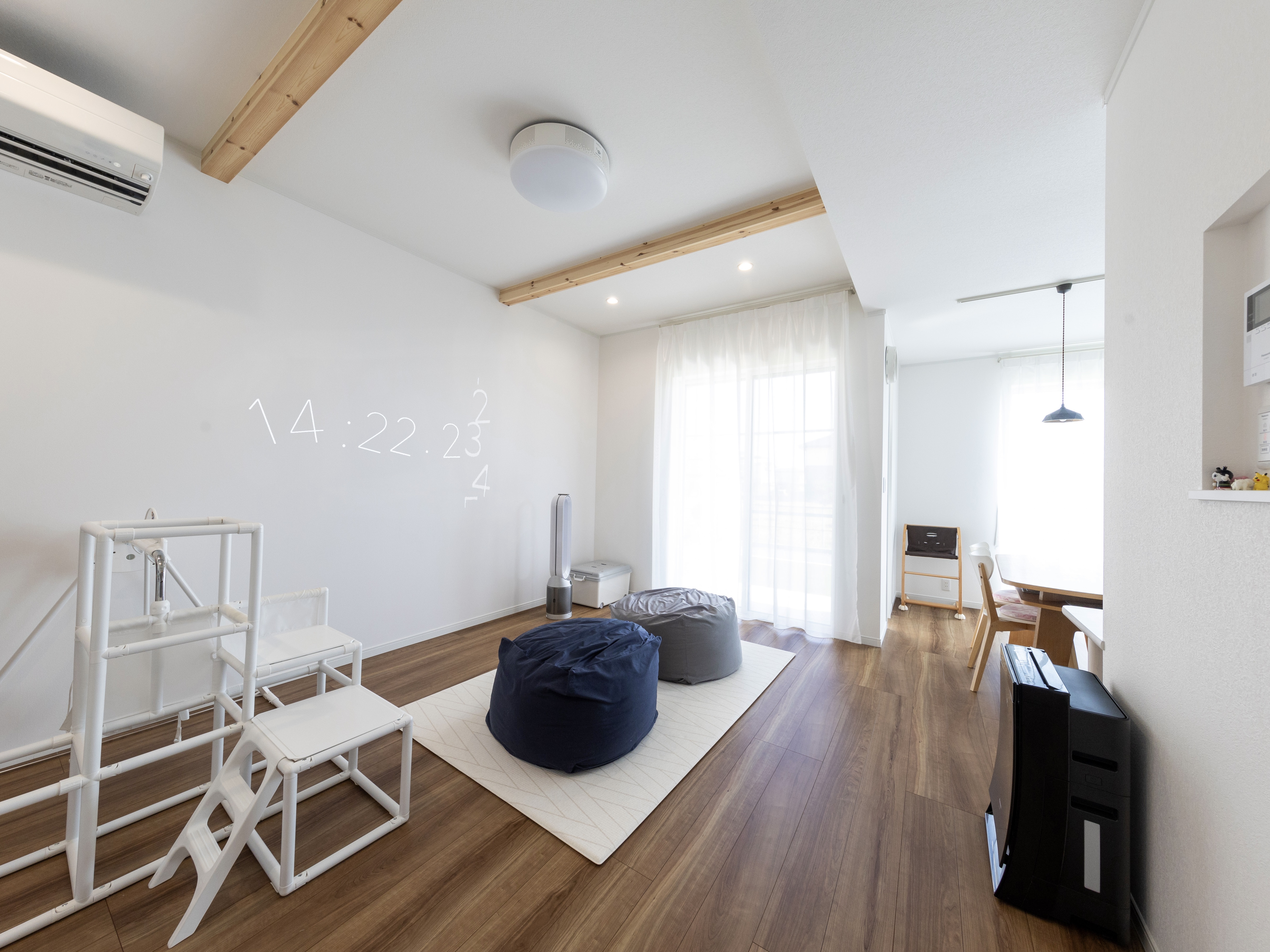 エスホーム｜リビングとダイニングを段差を付けたことで、リビングが道路からの視線を遮る形となり、外からの人目を気にすることなくリラックスして過ごせる。段差分リビングを狭くなったが、天井を2.7mに上げ、カーテンを天井近くに取り付けたことで、縦へ伸びる開放感を作っている。