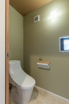 落ち着いた色合いの壁紙を採用したシンプルなトイレ空間。小窓から自然光が入り、明るく清潔な印象を与えるデザイン。