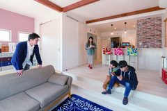 ダイニングとリビングの間につけた段差が、ゆるやかに空間を区切る。レンガ調のアクセントクロスと梁でナチュラルな印象に