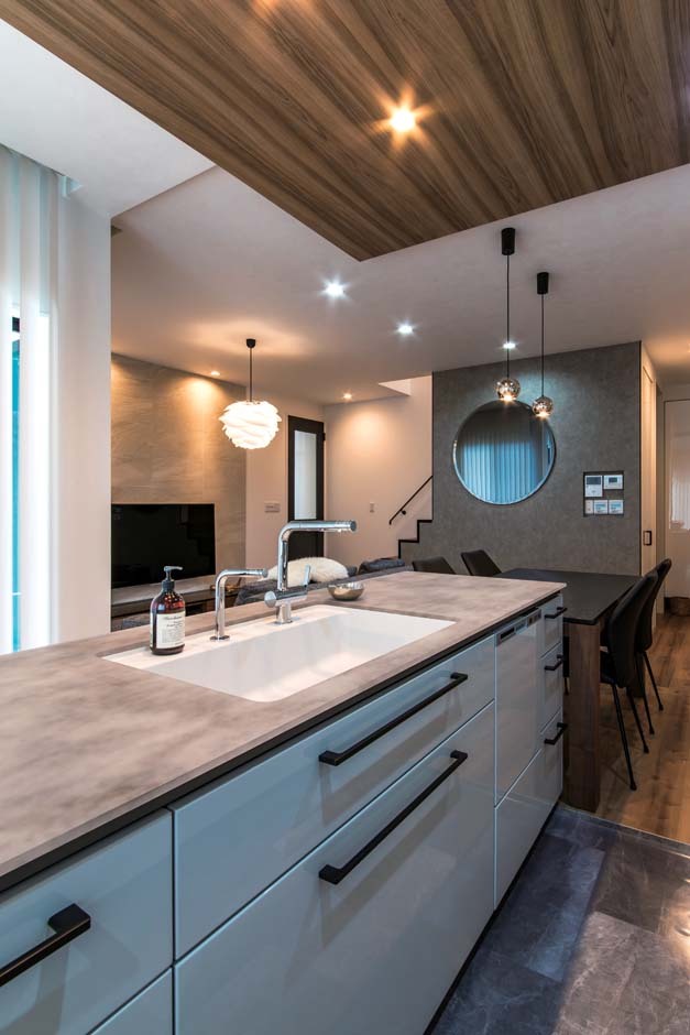 憧れのアイランドキッチンは、ダイニングテーブルを横付けにして便利な配膳動線に。ダイニングの壁に付けたお気に入りのスモークの丸鏡も空間に広がりを与える