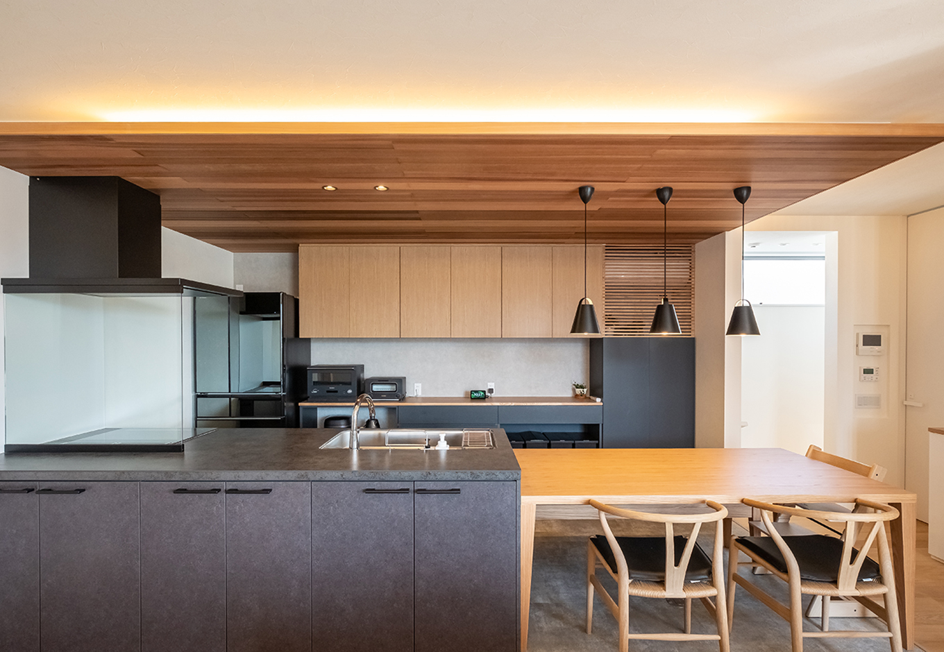 金子工務店/めぐみ不動産【デザイン住宅、子育て、建築家】木の温もりとアイアンブラックのマテリアル感で、大人の空間に仕上げたダイニングキッチン。キッチンに横付けのダイニングテーブルは、子どものスタディスペースなどマルチに活躍する