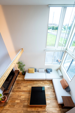 大きな窓から自然光が差し込む開放的なリビング。高い天井と広々としたスペースが心地よい空間を作り出している。