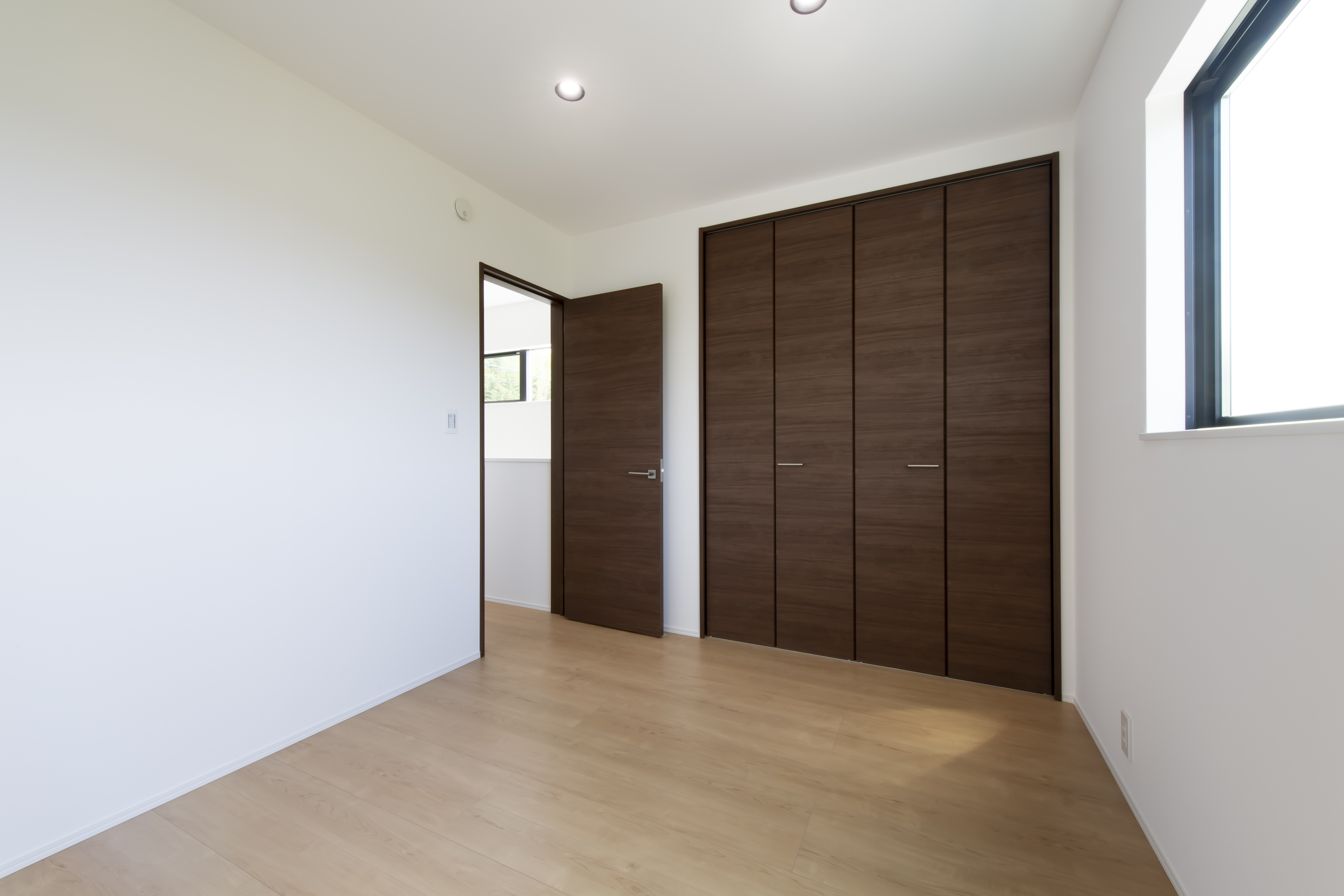 スズイチ｜大きなクローゼットが備わった居室。木目のドアとクローゼットが部屋全体に落ち着きを与えている。