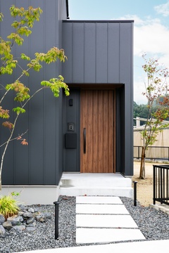 玄関アプローチには飛び石を採用。
木目調の玄関扉を採用し、外観のアクセントに。