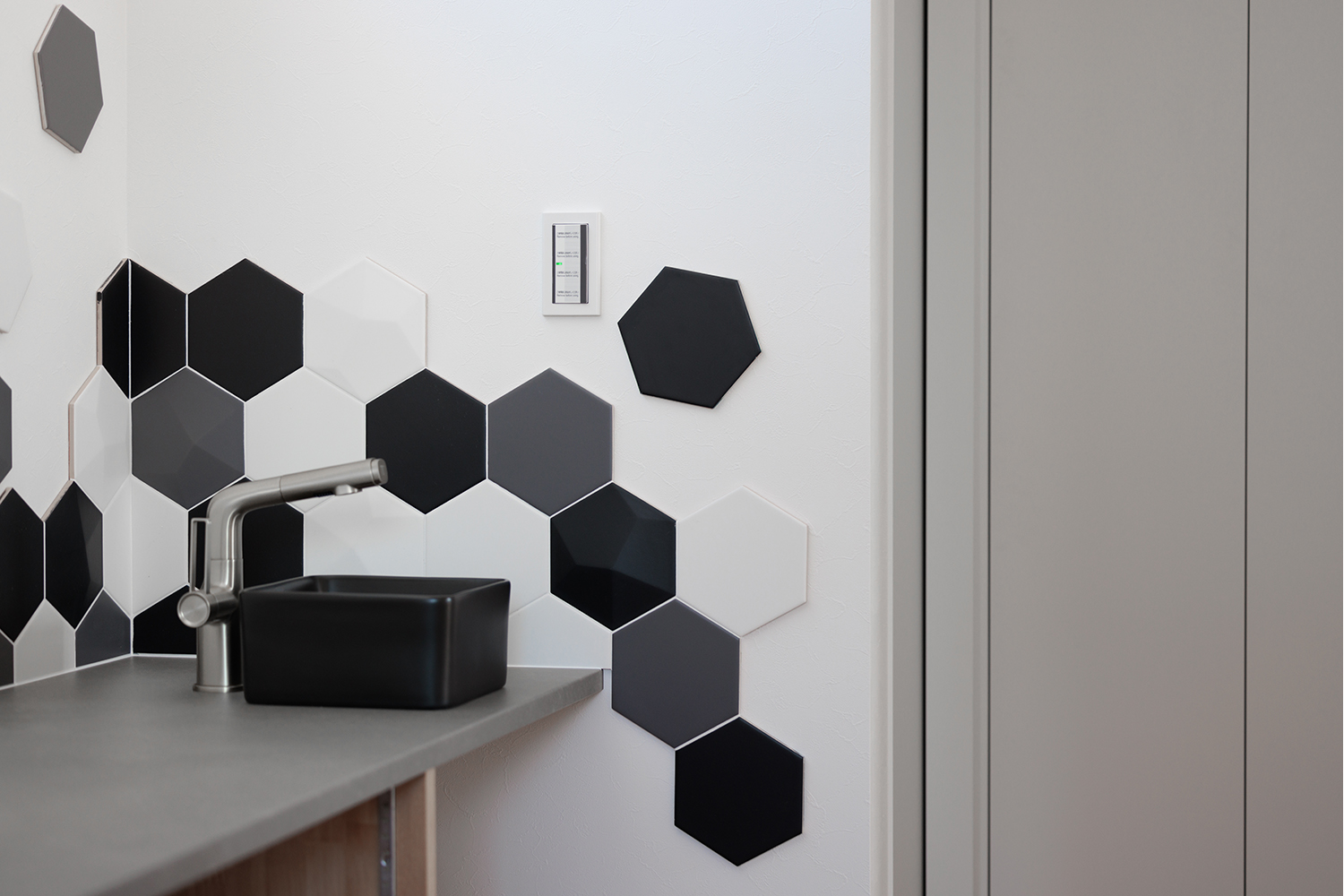 tact design firm【デザイン住宅、子育て、間取り】モダンなデザインが印象的な洗面スペース。黒と白のヘキサゴン柄が個性的でスタイリッシュな空間を演出している