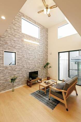 南面の大きな窓と吹抜けからたっぷりの光を取り入れるリビング。テレビステーションの石貼りの壁面が高級感を演出。超省エネ設計で低燃費な暮らしを実現