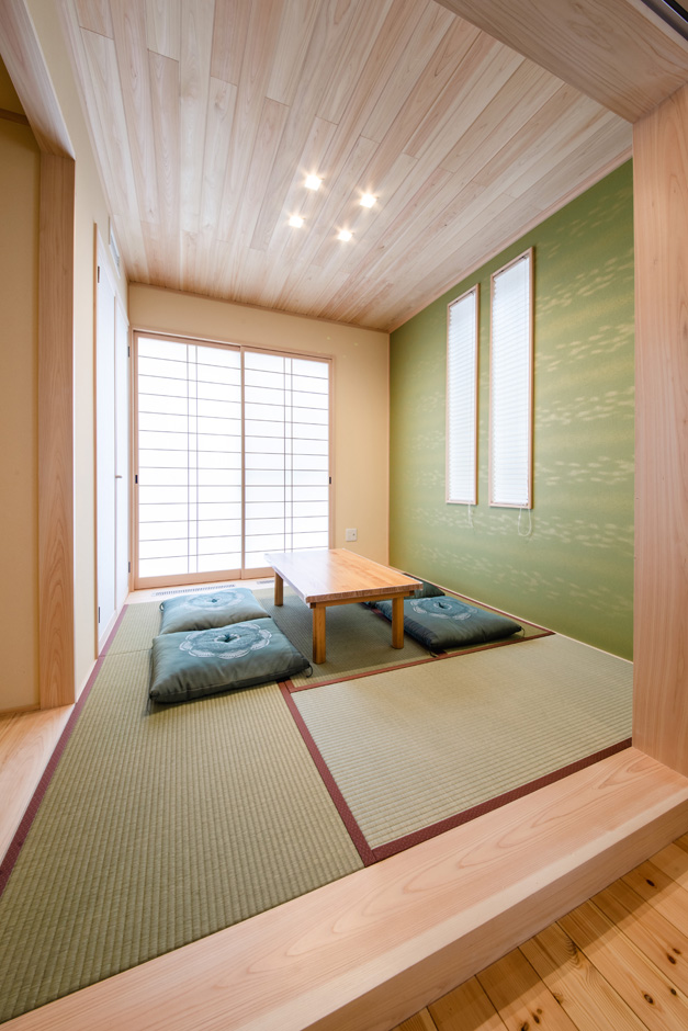 瀧口建設｜リビングに隣接する小上がりの和室。全館空調システムにより、無垢の床だけでなく、畳まで暖かくなるのがすごい。お茶をイメージしたデザインクロスは、奥さまのセンスで選んだ。障子を開けると坪庭の風情を楽しむことができる