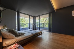 大きな窓から自然光が差し込むリラックスできる寝室。モダンなデザインのインテリアと広々としたスペースが心地よい空間を演出している。