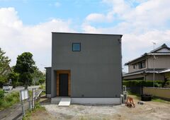 コンパクトでシンプルなフォルムの外観。庭の緑が映えるデザインで、機能的かつモダンな住まいを感じさせる。