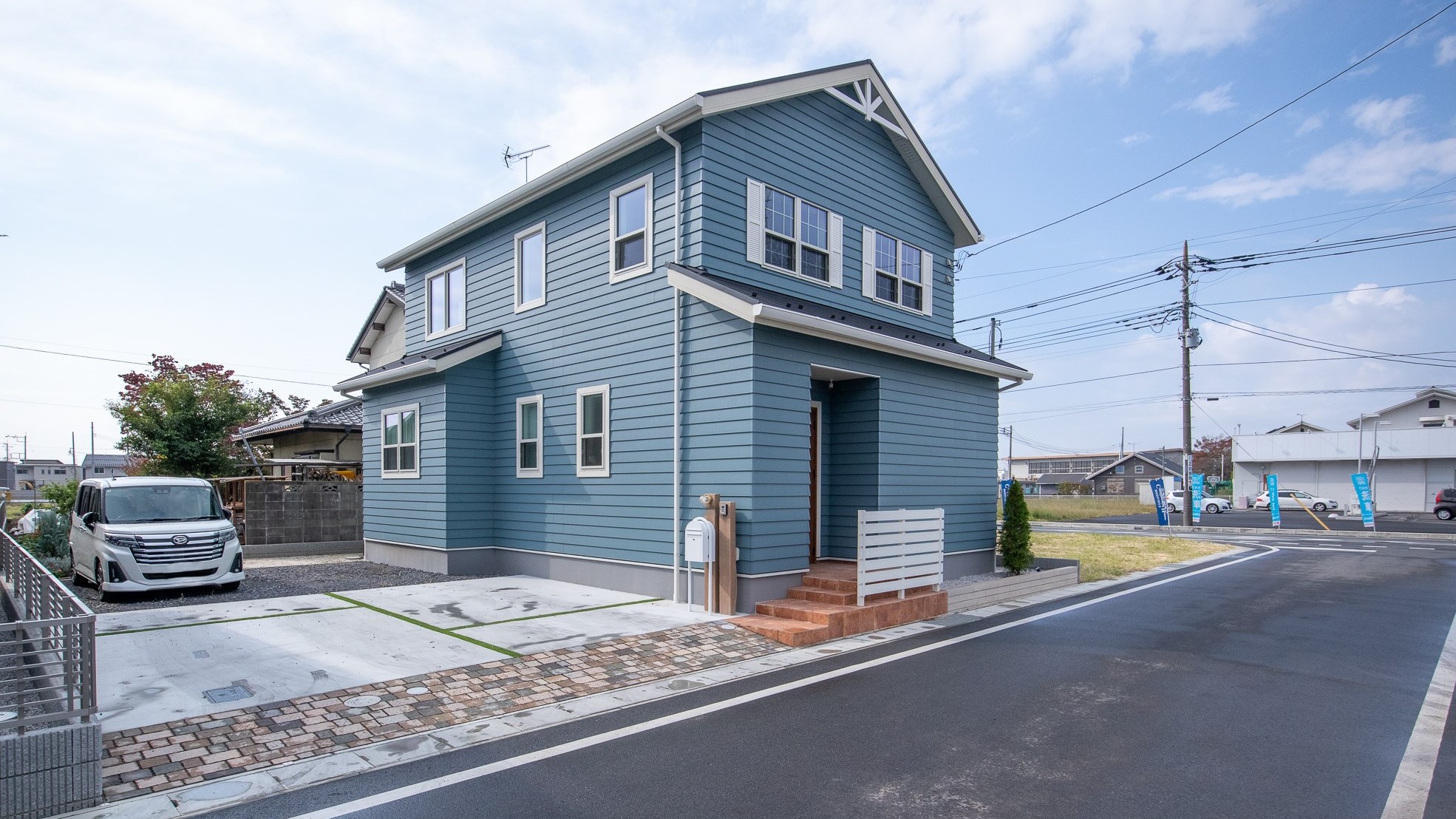 コンチネンタルホーム｜2階建ての美しい外観を持つ住宅。ブルーの外壁と白い窓枠が爽やかさを演出し、全体のデザインを引き立てている。