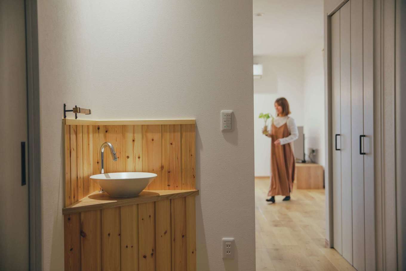 ほっと住まいる【デザイン住宅、自然素材、狭小住宅】玄関ホールに設けた来客用の手洗いコーナー。LDKの壁面収納は家族の上着類をしまうクローゼットとして利用