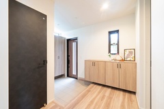 明るく開放的な玄関スペース。ナチュラルな木目の収納がアクセントとなり、来客を温かく迎える雰囲気を作り出している。