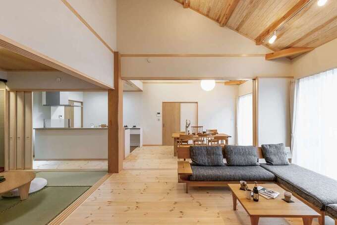 勾配天井のリビング。床には厚さ30mmの松の天然木、壁には珪藻土を採用。冬でも天然木の床が保温性を発揮して、足元を暖かく保つ。引き戸を閉めれば、それぞれのスペースを分けて使うことができる