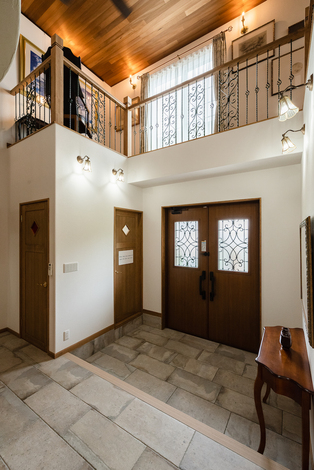 クラシックな印象の観音開きのエントランスドア。上部には2階の回廊を巡らせている