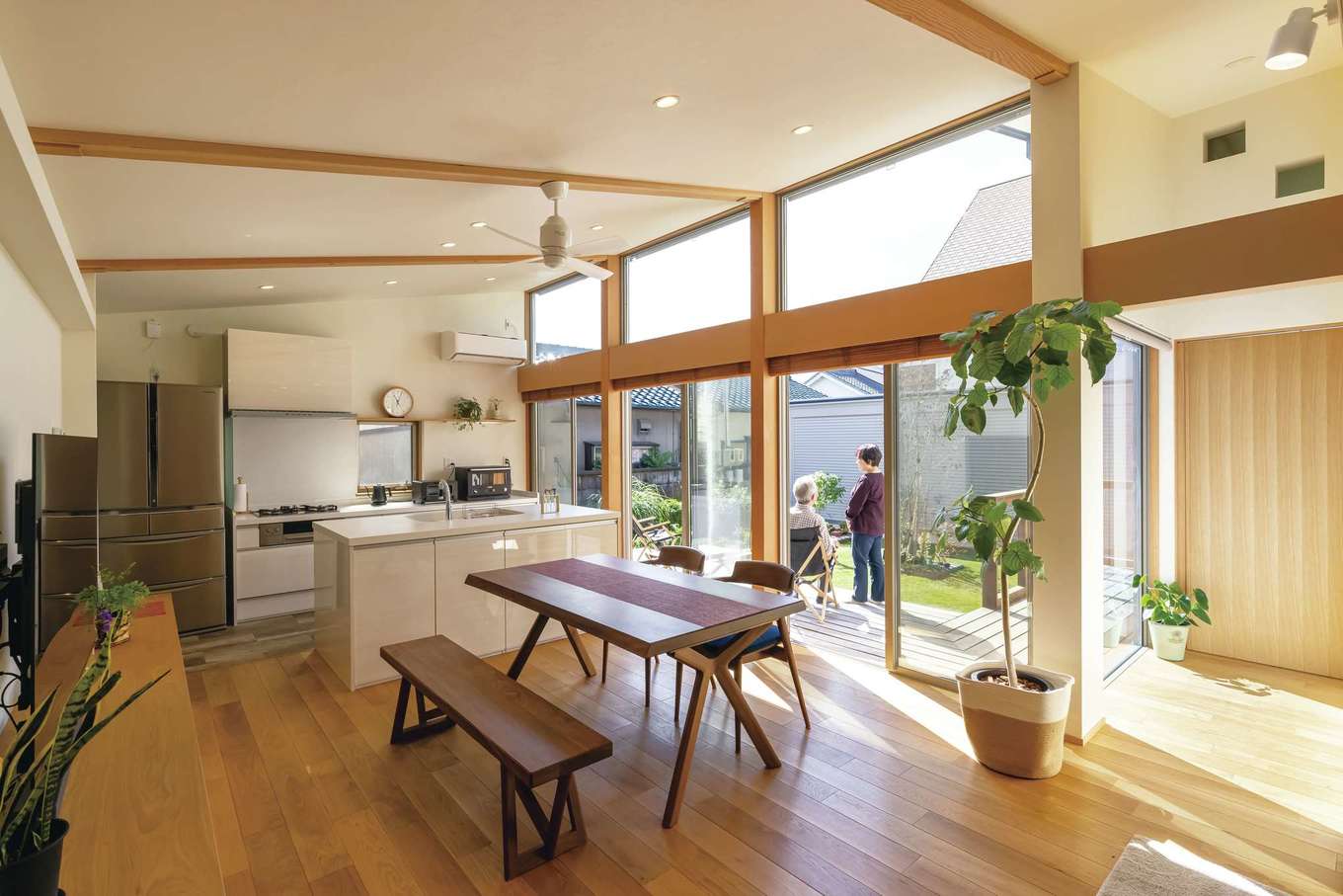 神谷綜合建設 カミヤの家【デザイン住宅、収納力、平屋】玄関ホールを抜けると、大開口の窓を持つLDKがお出迎え。落ち着きのあるヨーロピアンオークの床をベースに、木目の詰まった見た目にも美しいピーラー（米松）の化粧柱や、壁面にレッドシダーを採用することで、程よい木質感を演出。壁の一部にあしらった、通気性や透湿性に優れたコットンクロスが窓からの光を優しく反射し、室内を照らす。L字のプランにしたことで部屋のどこからでも庭を望むことができ、明るく、居心地のよい空間になった