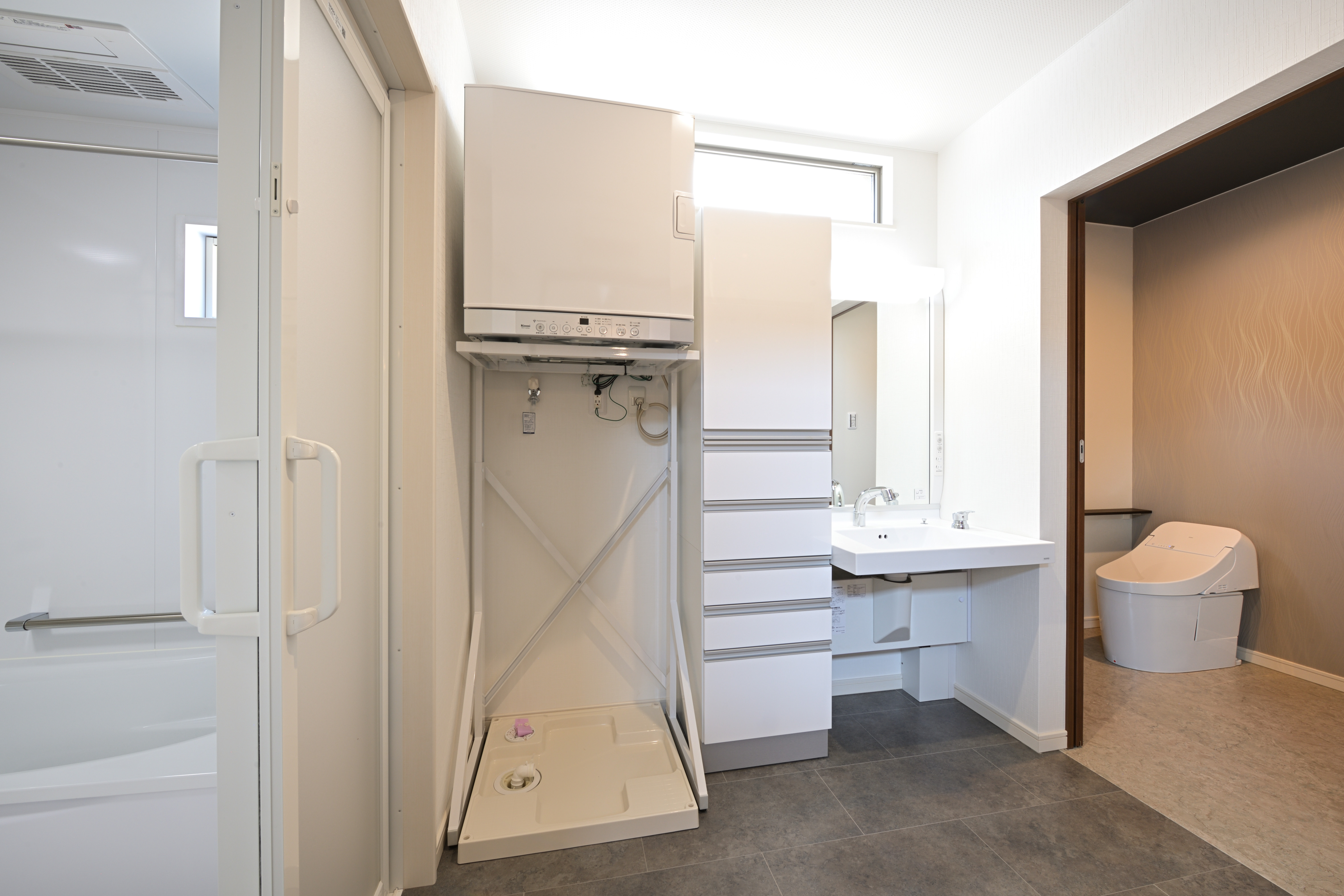 芳賀建工【子育て、収納力、間取り】「乾太くん、最高！」と奥さまが全幅の信頼を寄せるガス衣類乾燥機を採用した洗面脱衣室。約2.7畳あるので、4人家族でも窮屈に感じない。トイレにも直結して重宝している