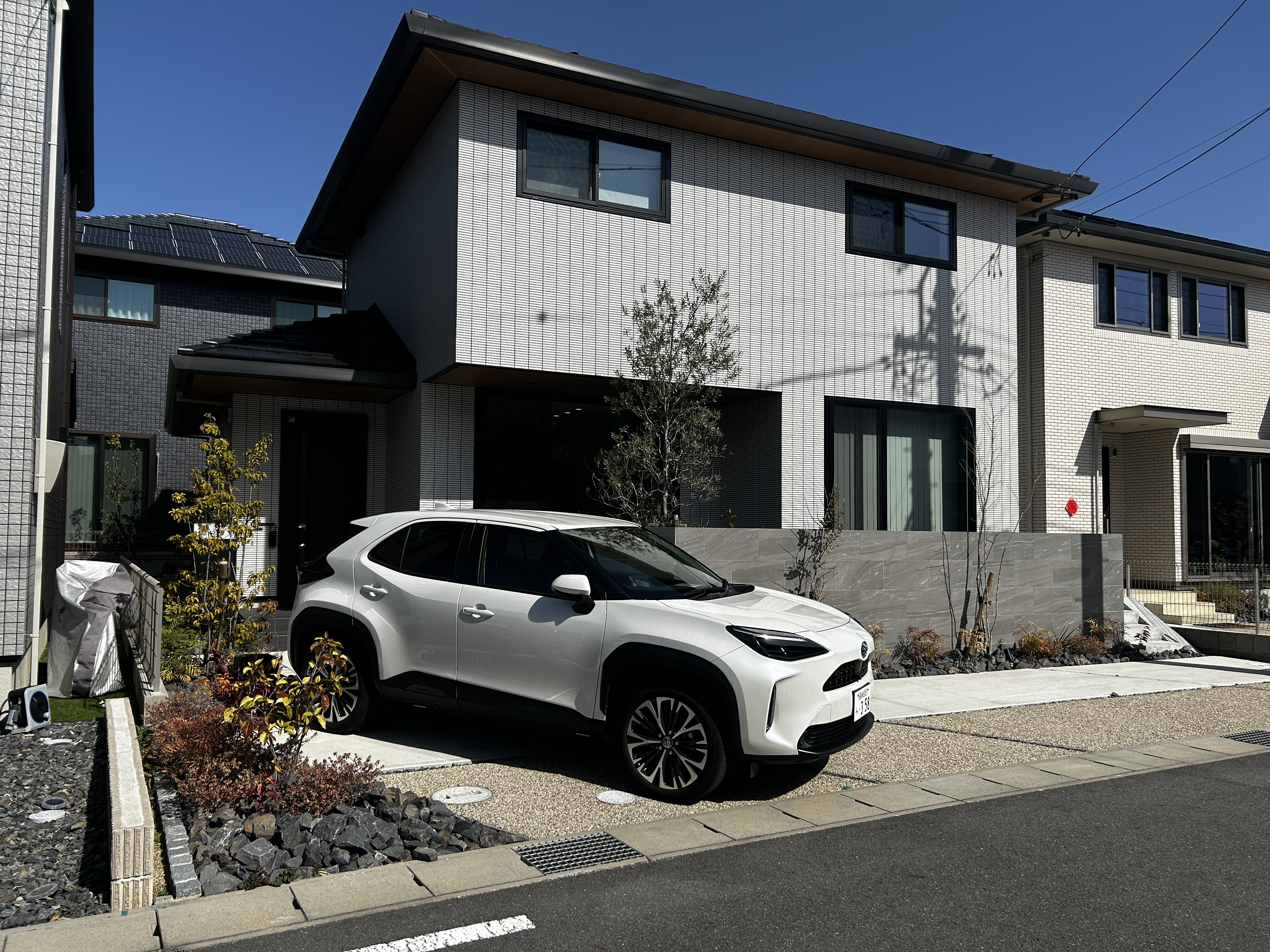 パナソニックホームズ中部第一支社 愛知第一支店・愛知第二支店｜モダンな外観の住宅。白とグレーの配色がシックで、周囲の環境に溶け込んでいる。駐車スペースには使いやすいデザインが施されている。