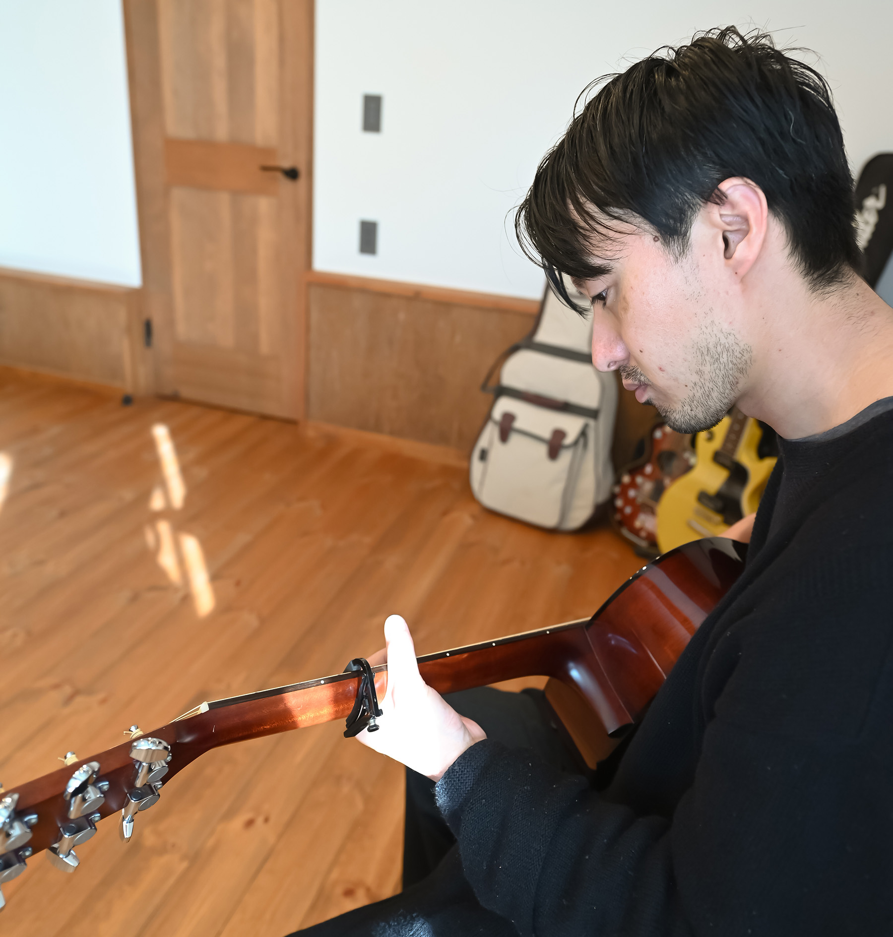 ネクストハウスデザイン｜ギターを弾くシーンが印象的な音楽ルーム。木材を多用した温かみのあるインテリアが特徴的で、音楽に集中できる落ち着いた空間。