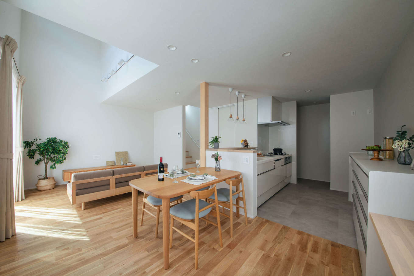 DAITOKU（大得工務店）【子育て、省エネ、建築家】木のあたたかみを感じるナチュラルテイストのLDK。キッチンを中心にぐるりと回れる動線が家事時間を短縮してくれる。リビングの吹抜けへと視線が抜け、実面積よりも広く感じられる