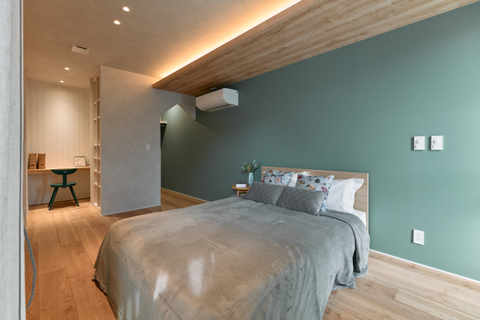 木のぬくもりが感じられる広々とした寝室。柔らかな間接照明が心地よい雰囲気を出し、リラックスできる空間を演出している。