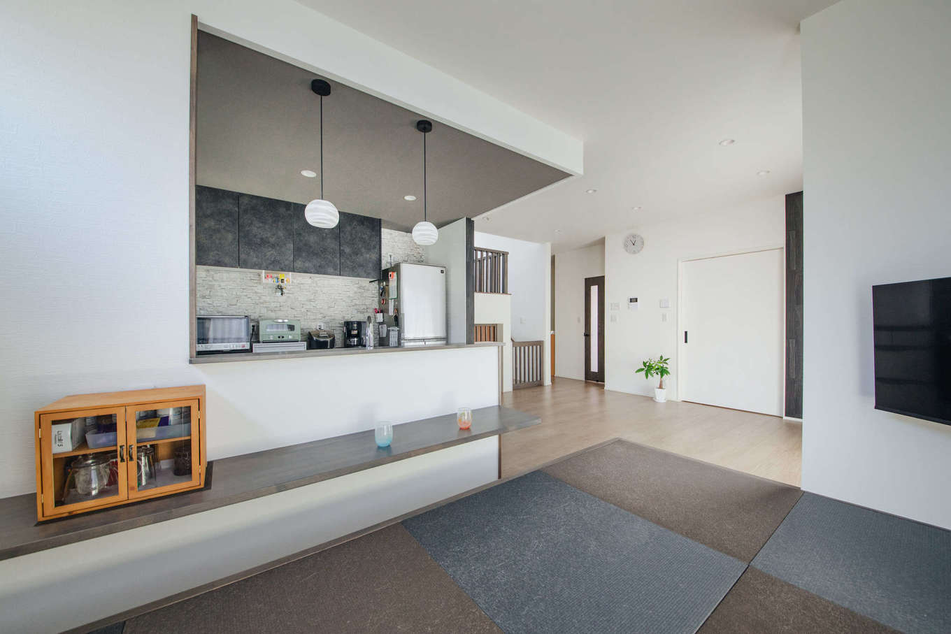 エフエフ住宅【ペット、平屋、スキップフロア】小上がりの畳を黒にすることで、キッチンやアクセントクロスと色を統一。下がり天井にペンダント照明をプラスして、おしゃれな居酒屋風の空間にコーディネート
