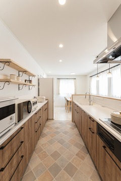 使いやすさを重視したキッチン。吊り棚やオープンシェルフで収納力も兼ね備えたデザインが特徴。