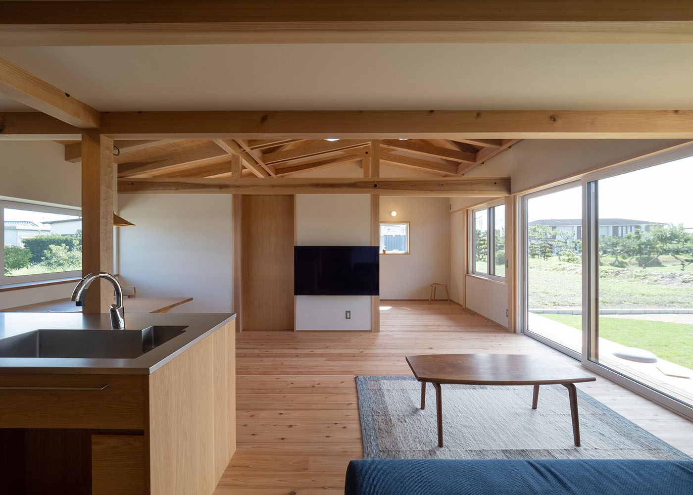 石牧建築【デザイン住宅、子育て、平屋】LDKの大開口からは、たっぷりの光と風が招かれる。テレビの裏側は約10畳のフリースペースで、将来的に子ども部屋や趣味部屋など、多用途に使うことができる