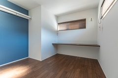 寝室には、ちょっとした作業ができるカウンターが備えられています。落ち着いた色味の床とブルーのアクセント壁がやさしい雰囲気をつくり、自分時間を静かに過ごせそうな空間です。