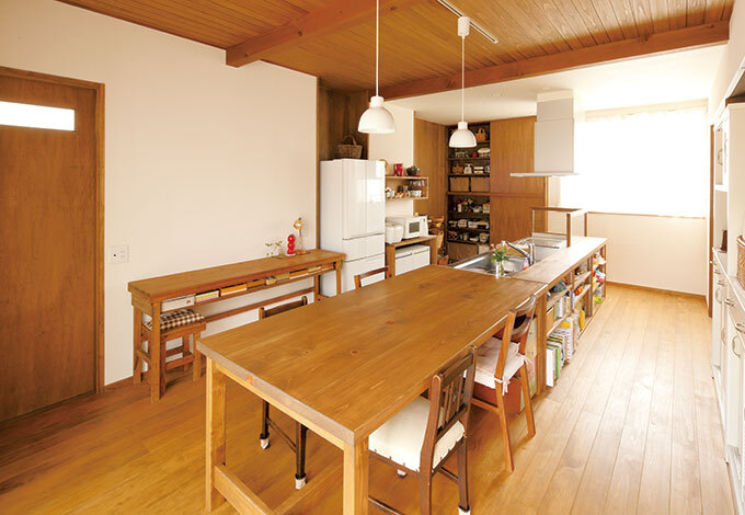 ご主人が腕を振るうことも多いアイランドキッチン。そのまま横付けにしたダイニングテーブルはオリジナル造作。木の机、白い食器棚は以前1 から使っていたものを使用ー