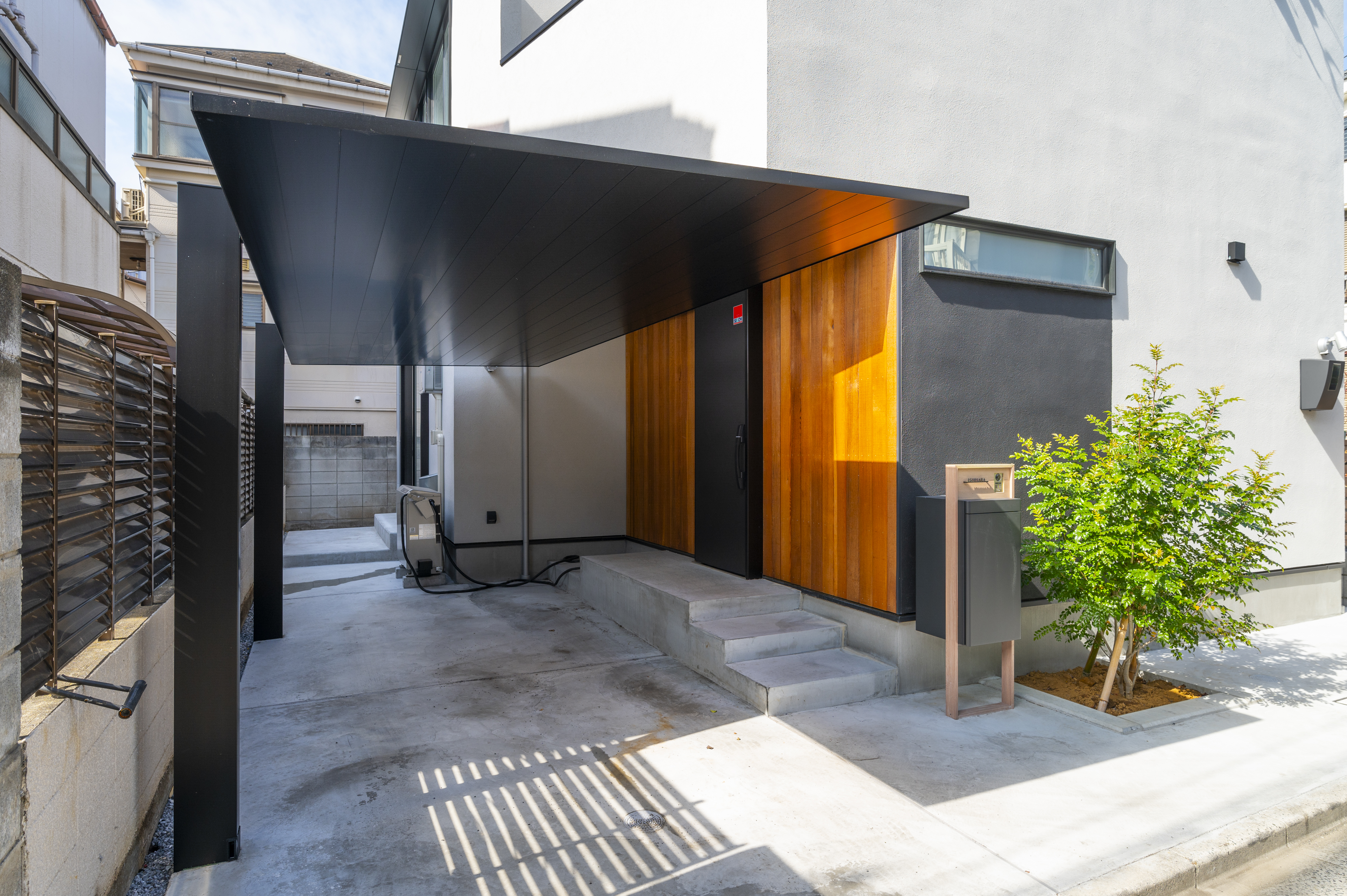 オネストアーク｜モダンなデザインが魅力の住宅外観。黒と木目のコントラストが印象的であり、エントランスまでのアプローチがスタイリッシュな印象を与える。