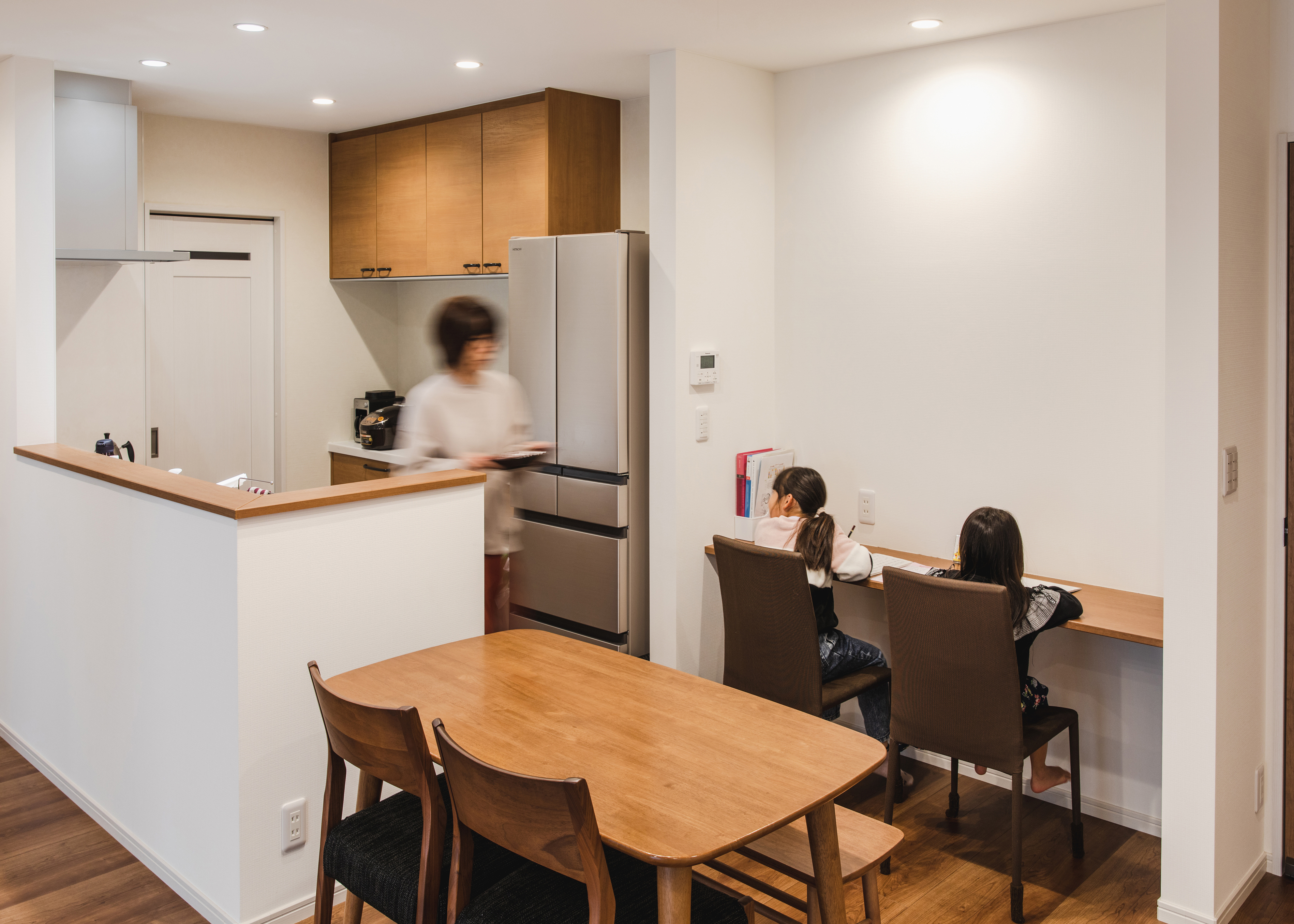 ナイスホーム【収納力、デザイン住宅、間取り】キッチンのすぐそばにスタディコーナーを造作。子どもたちはママに見守られながら勉強できて、奥さまは料理しながら子どもたちの様子が見えるので、お互いに安心できる。白い壁はマジック仕様で、プリントを貼り付けられる