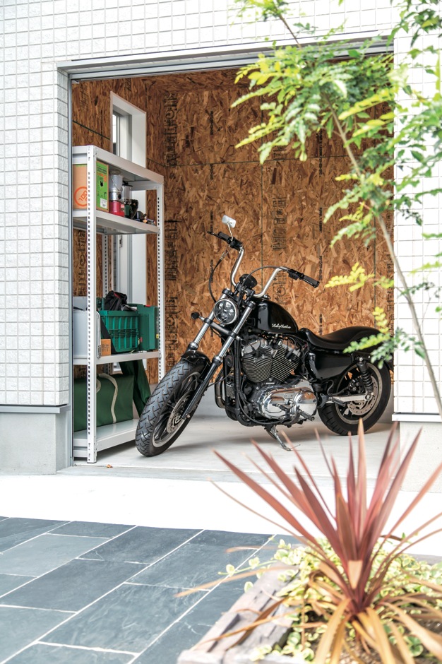 アフターホーム【1000万円台、デザイン住宅、趣味】大型バイクが収まるガレージ。子ども部屋にエンジン音が響くのを防ぐため、2階部分にはご主人の書斎を配置。中庭と往き来もできる開口部も設けた