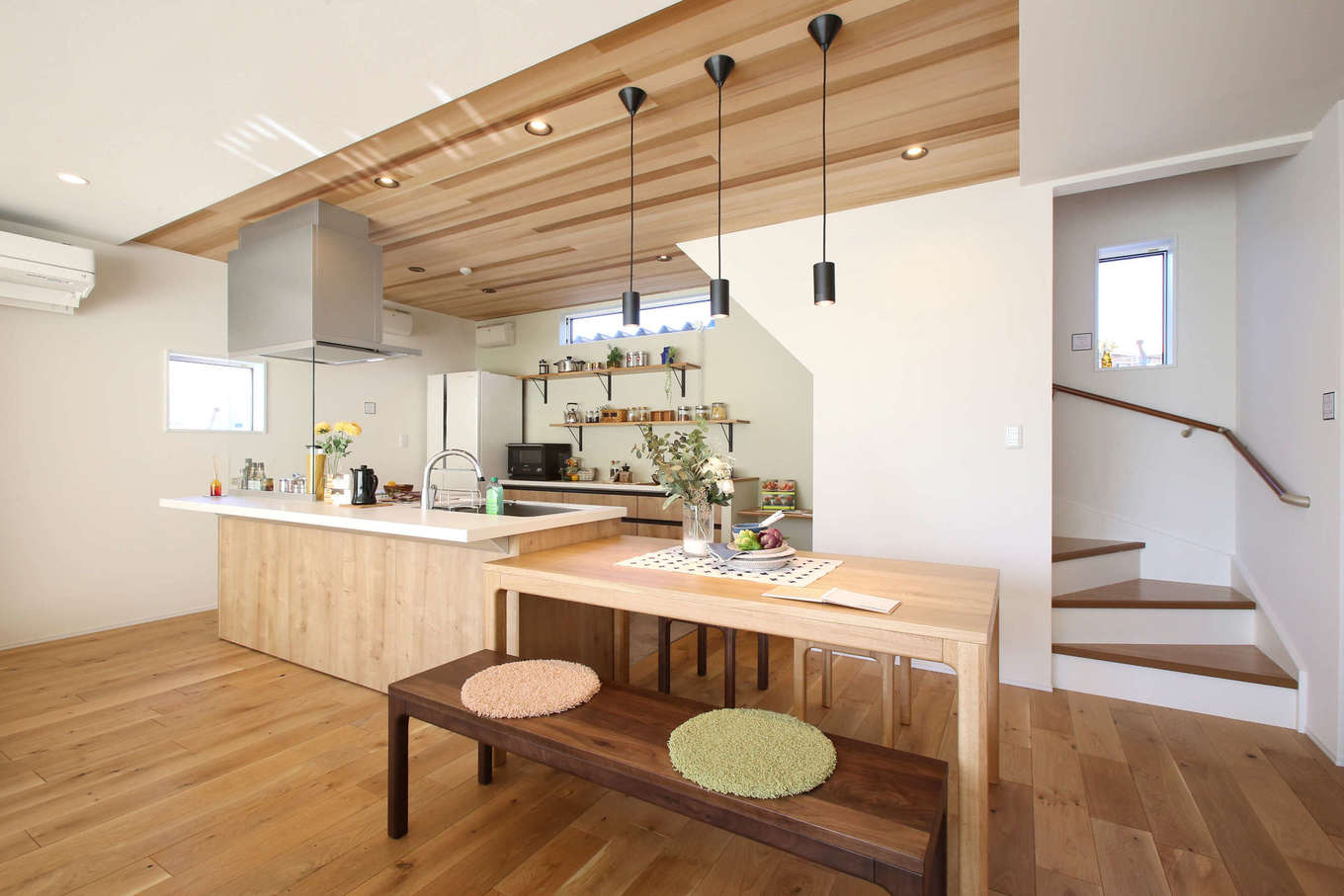 片桐建設【デザイン住宅、間取り、スキップフロア】ダイニングテーブルをキッチンの真横に配置したことで、配膳や後片付けが楽になり、奥さまの家事時間を短縮できる。子どもたちが学校から帰ってきて「ただいま」を言ってから2階に上がるリビング階段を設けた