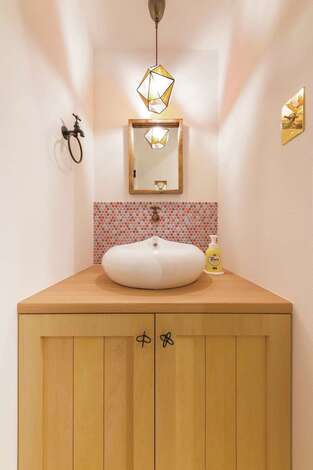 おしゃれなボウル、タイル、鏡、照明、取っ手がバランス良く調和したゲスト用の手洗いコーナー
