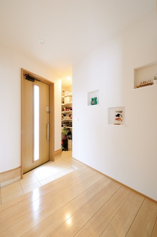 玄関の白壁にニッチの小物で彩りを。シューズクロークには靴や荷物をたっぷり収納